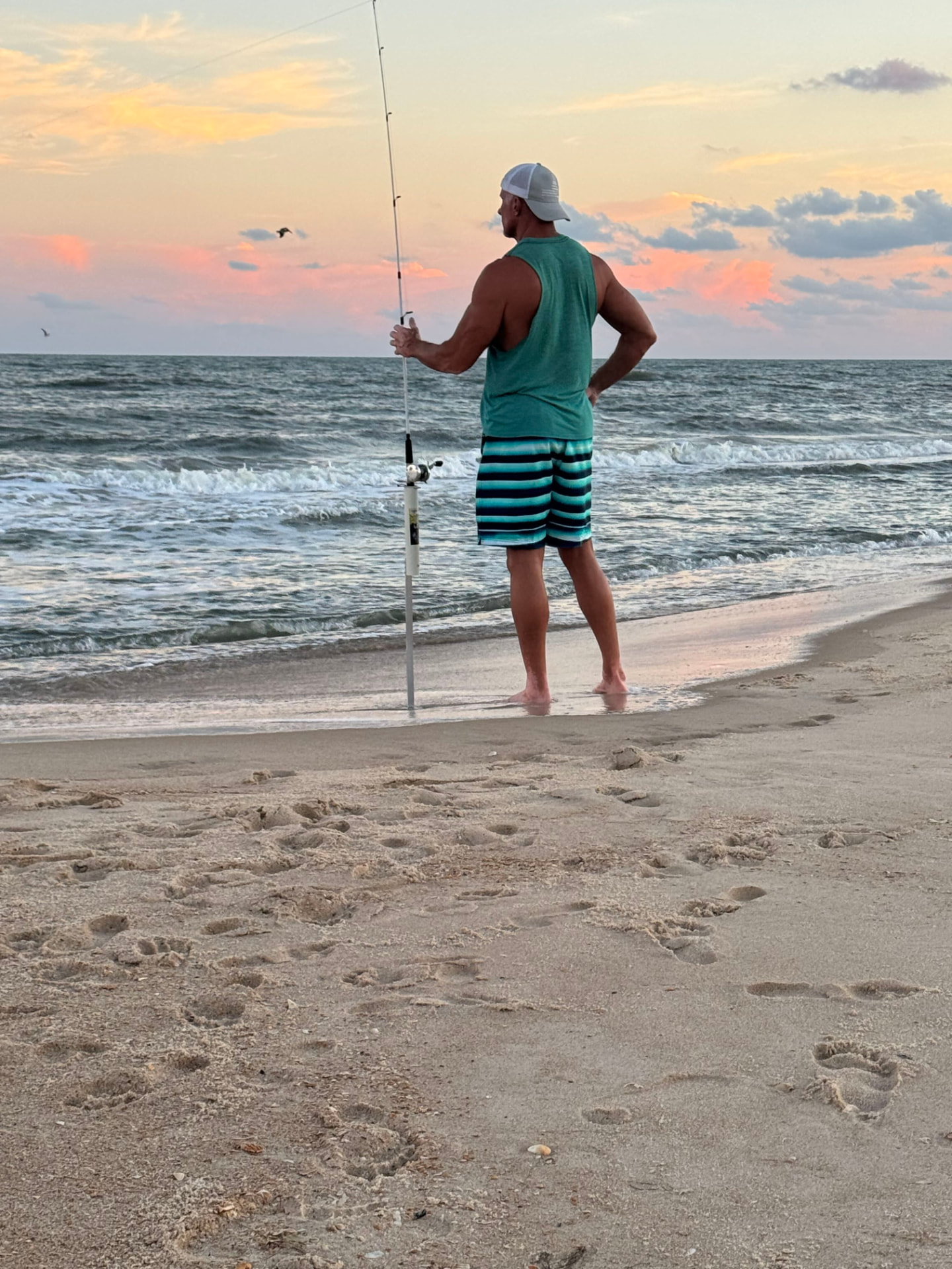 Shawn Greenway surf fishing at the edge of the water at sunset